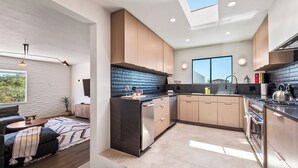 Una cucina moderna con isola centrale, mobili in legno, zoccolo nero e un lucernario.