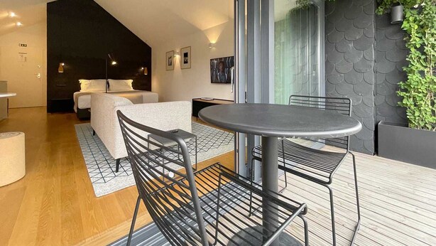 Une chambre d’hôtel moderne avec une grande fenêtre, un lit confortable, une petite table et une chaise.