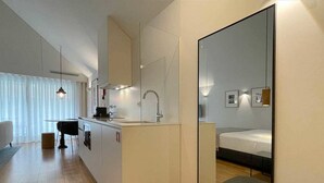 Une chambre d’hôtel moderne équipée d’une kitchenette, d’un lit et d’un grand miroir.