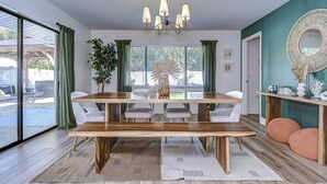 A dining area with a wooden table, white chairs, and a chandelier. - Beautifully Decorated Largo Home,  close to beaches, Pinellas Trail & Johns Lake (Largo)