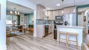 A modern kitchen with light wood cabinets, stainless steel appliances, and a central island with stools. - Beautifully Decorated Largo Home,  close to beaches, Pinellas Trail & Johns Lake (Largo)