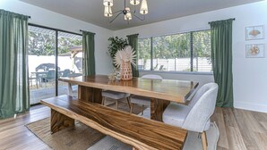 A dining area with a wooden table, benches, and chairs. There is a chandelier above the table. - Beautifully Decorated Largo Home,  close to beaches, Pinellas Trail & Johns Lake (Largo)