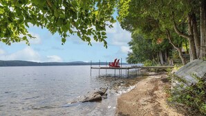 Une jetée au bord du lac, avec des chaises rouges, une eau cristalline et une rive bordée d’arbres.