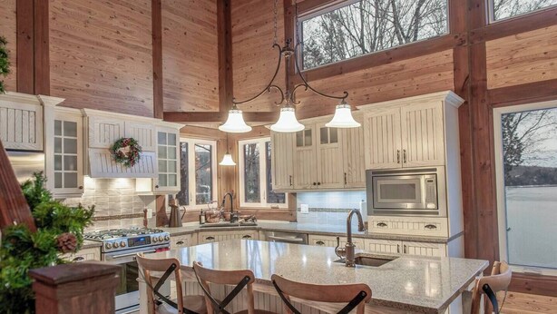 Une cuisine spacieuse avec des meubles en bois, un grand îlot central et des luminaires suspendus.