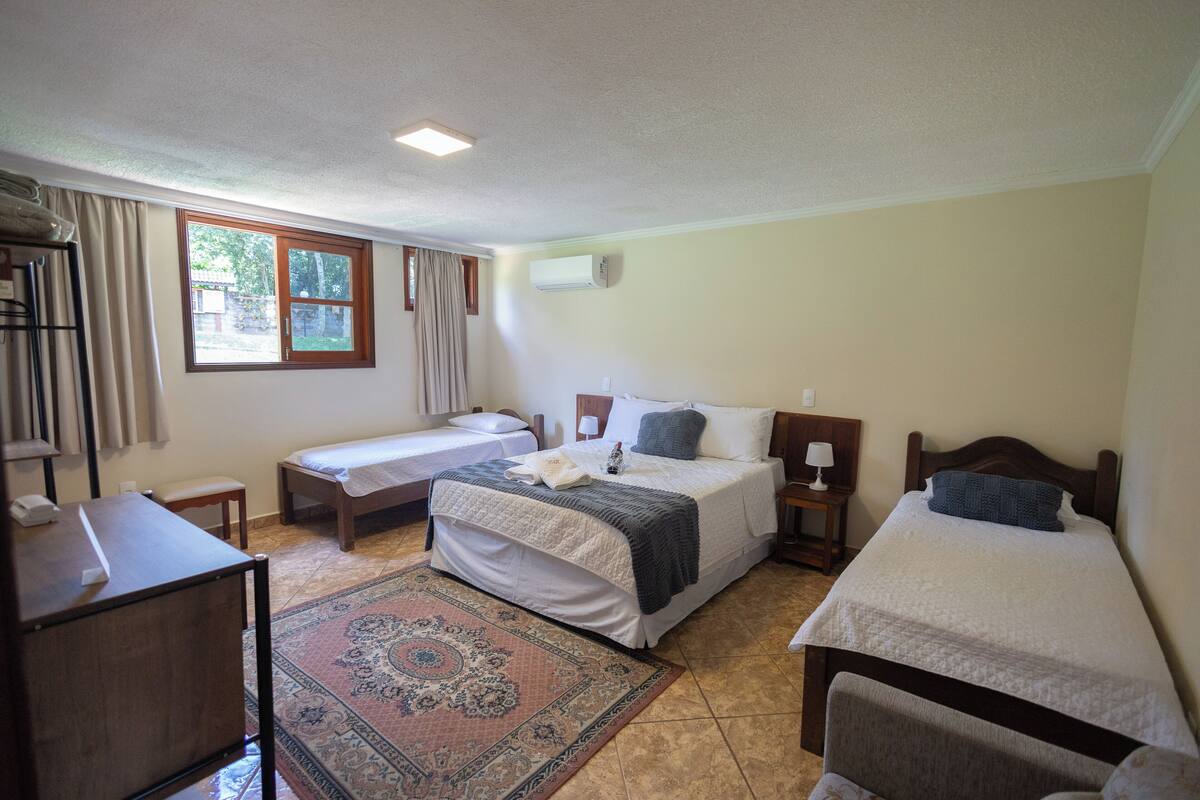 Ein Schlafzimmer mit zwei Einzelbetten, einem Schreibtisch, einem Stuhl, einem kleinen Tisch und einem Fenster mit Vorhängen.