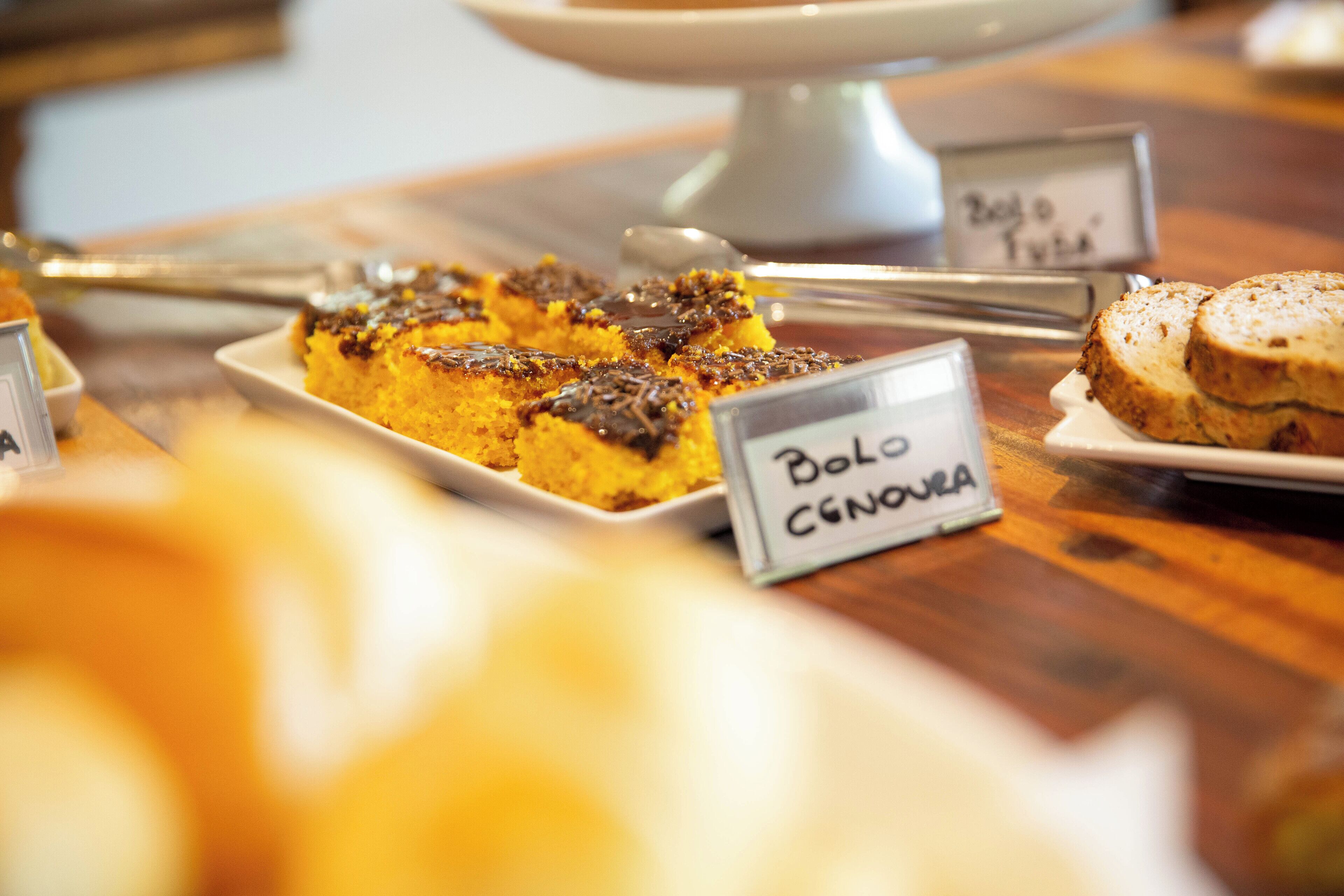 Un présentoir de desserts avec une pancarte indiquant « Bolo Cegonha ».