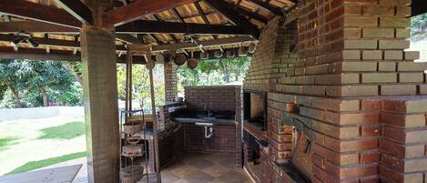 An outdoor kitchen with a brick oven, a sink, and a grill.