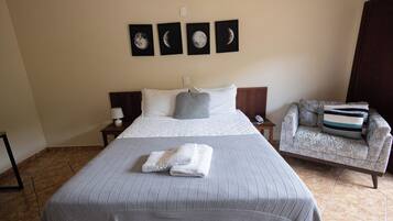 A hotel room with a large bed, a chair, and four moon phase wall art.