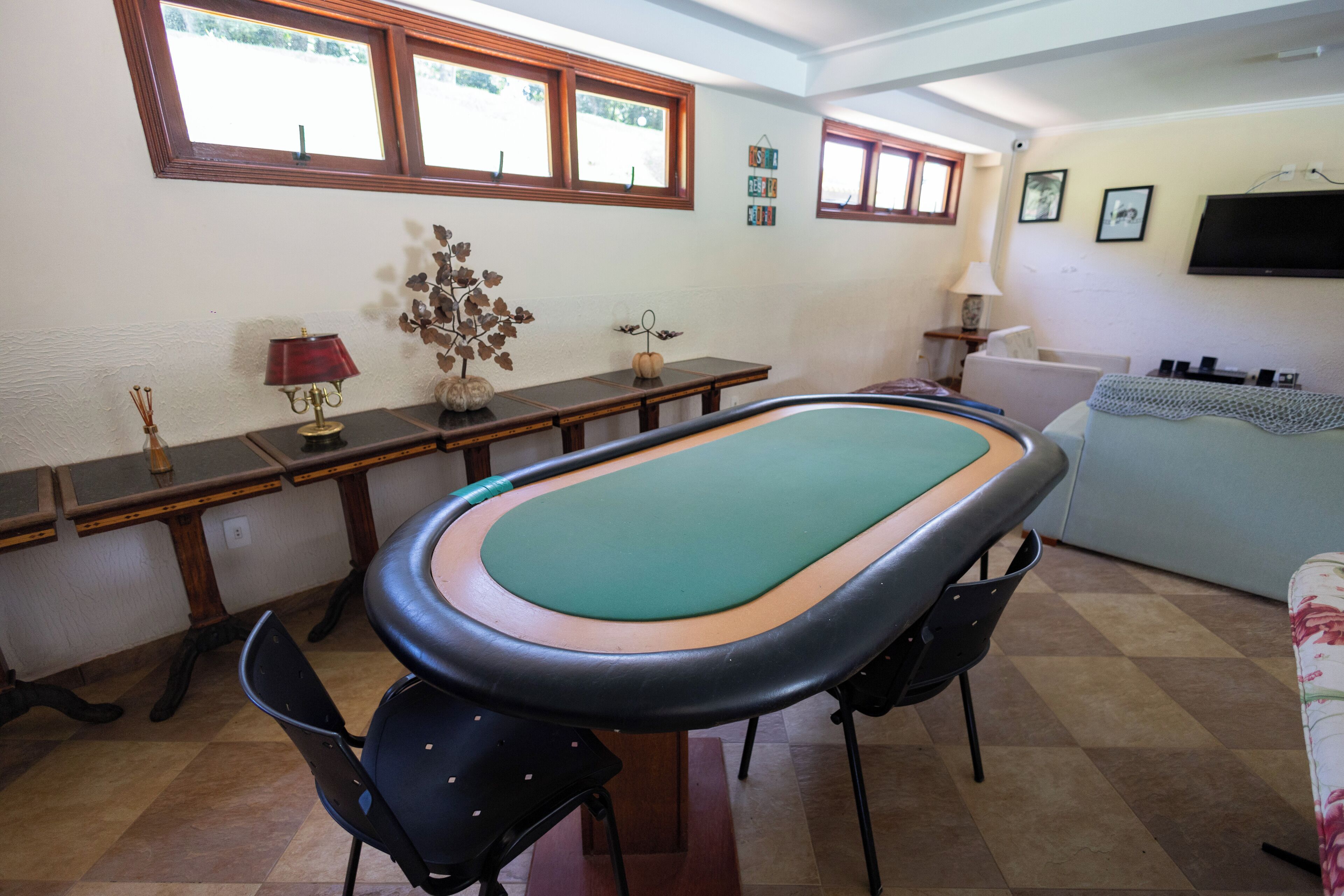 A room with a pool table, a sofa, a lamp, and a television on the wall.