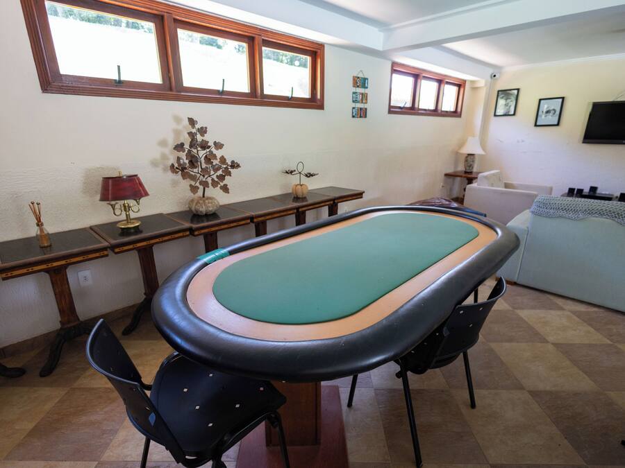A room with a pool table, a sofa, a lamp, and a television on the wall.