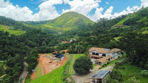 A hillside property with a house featuring a sloped roof, solar panels, and a garden. - Pousada Costa Rielli (Águas de Lindóia)