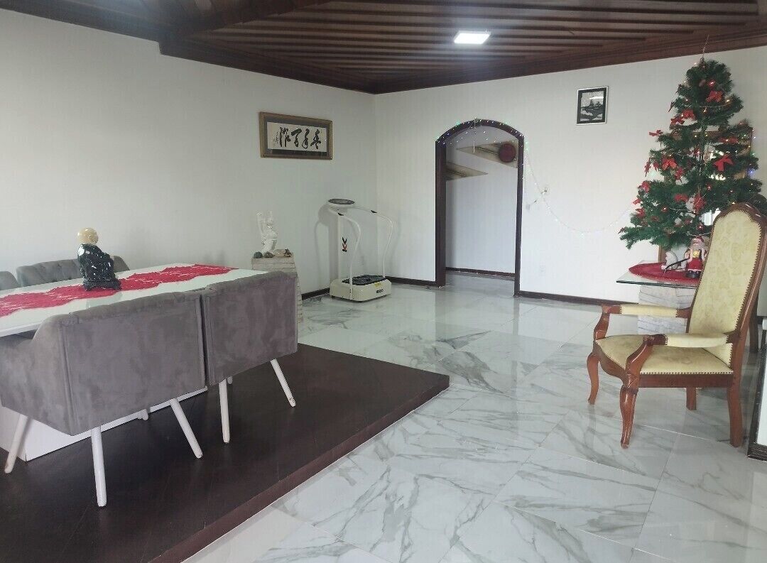 A dining area with a marble floor, a table with a red and white tablecloth, a Christmas tree, and a chair.