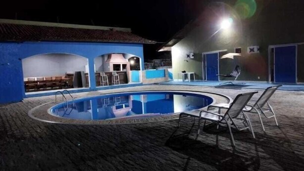 Une piscine extérieure à la forme incurvée, entourée d’un espace abrité comprenant des sièges et un petit bar.