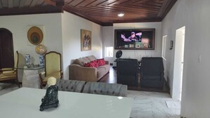 Un salon comprenant un téléviseur, un canapé, une table à manger et une statue décorative.