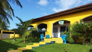 Un bâtiment jaune avec un toit recouvert de tuiles, un escalier menant à l’entrée et un drapeau au-dessus de la porte.