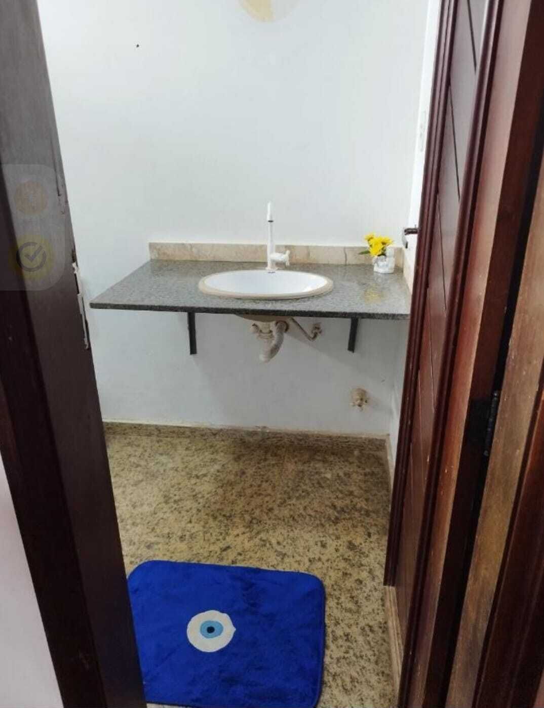 Une petite salle de bain avec un lavabo blanc, un miroir et un tapis bleu sur le sol.