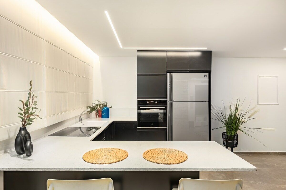 A modern kitchen with a central island, stainless steel appliances, and minimalist decor.