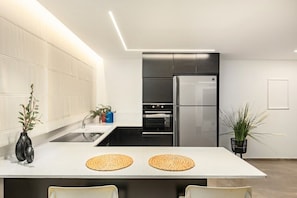 A modern kitchen with a central island, stainless steel appliances, and minimalist decor.
