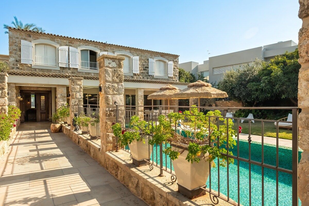 A stone building with a pool, potted plants, and outdoor seating.
