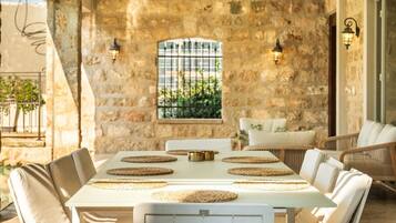 A stone-walled room with a table set for four, surrounded by cushioned chairs.