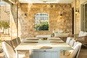 A stone-walled room with a table set for four, surrounded by cushioned chairs.