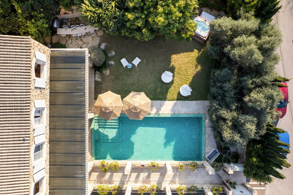An aerial view of a property with a swimming pool, lounge chairs, and a patio area.