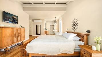 A bedroom with a wooden bed, a wooden nightstand, a TV mounted on the wall, and a decorative wall piece.