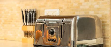 A toaster on a kitchen counter with a brick wall in the background.