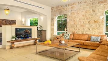 A living room with a stone wall, a sofa, a coffee table, and a TV mounted on the wall.