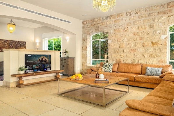 A living room with a stone wall, a sofa, a coffee table, and a TV mounted on the wall.