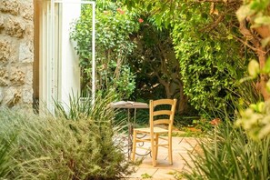 Ein Garten-Terrasse mit Tisch und Stuhl, umgeben von üppigem Grün und einer Steinmauer.