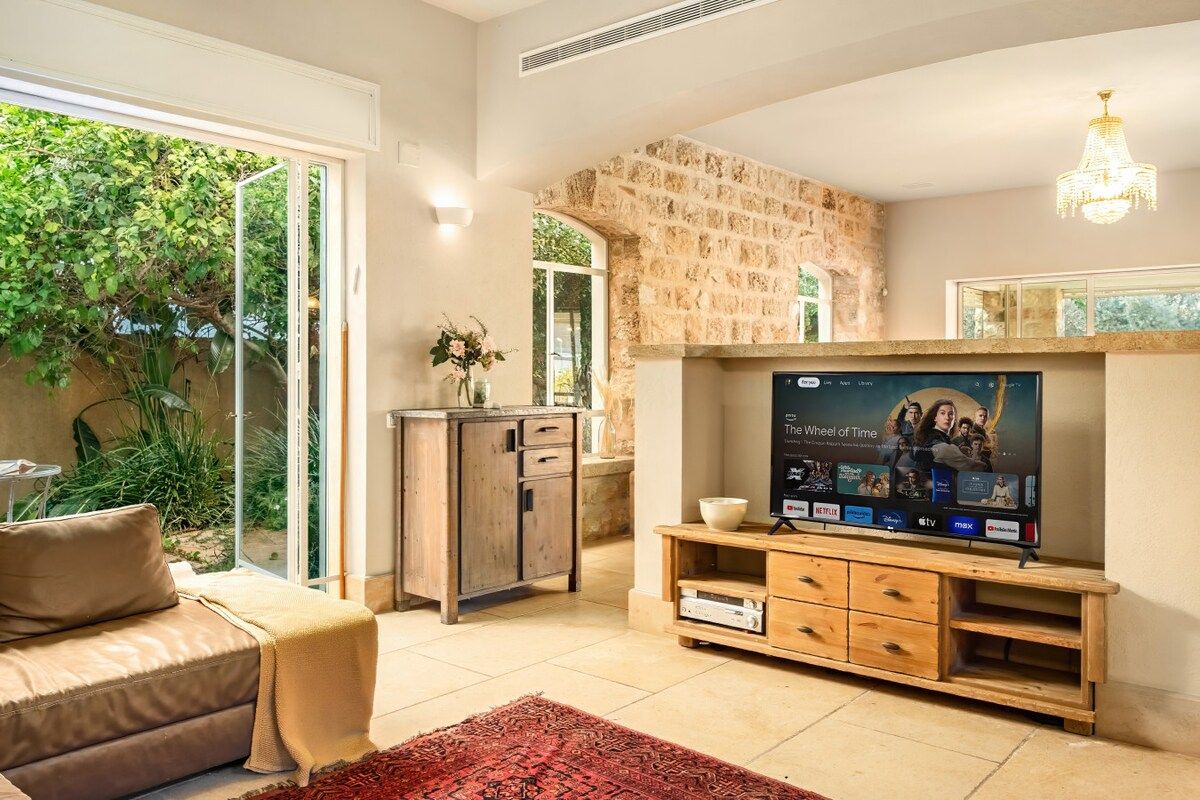 Una sala de estar con pared de piedra, televisor, sofá y mesa de centro.