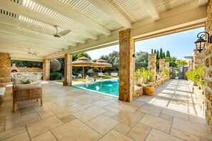 Relax by the pool in a serene outdoor space with a pergola, lounge chairs, and a dining table.