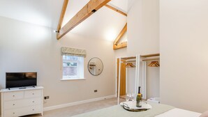 A bedroom with a bed, a dresser, a television, a window, a mirror, and a closet. - The Stables - UK46003 (Cranswick, near Driffield)