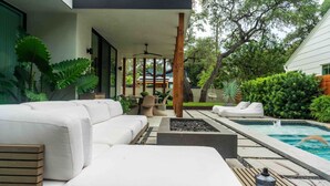 Ett modernt utomhusområde med pool, vita soffor och en pergola.