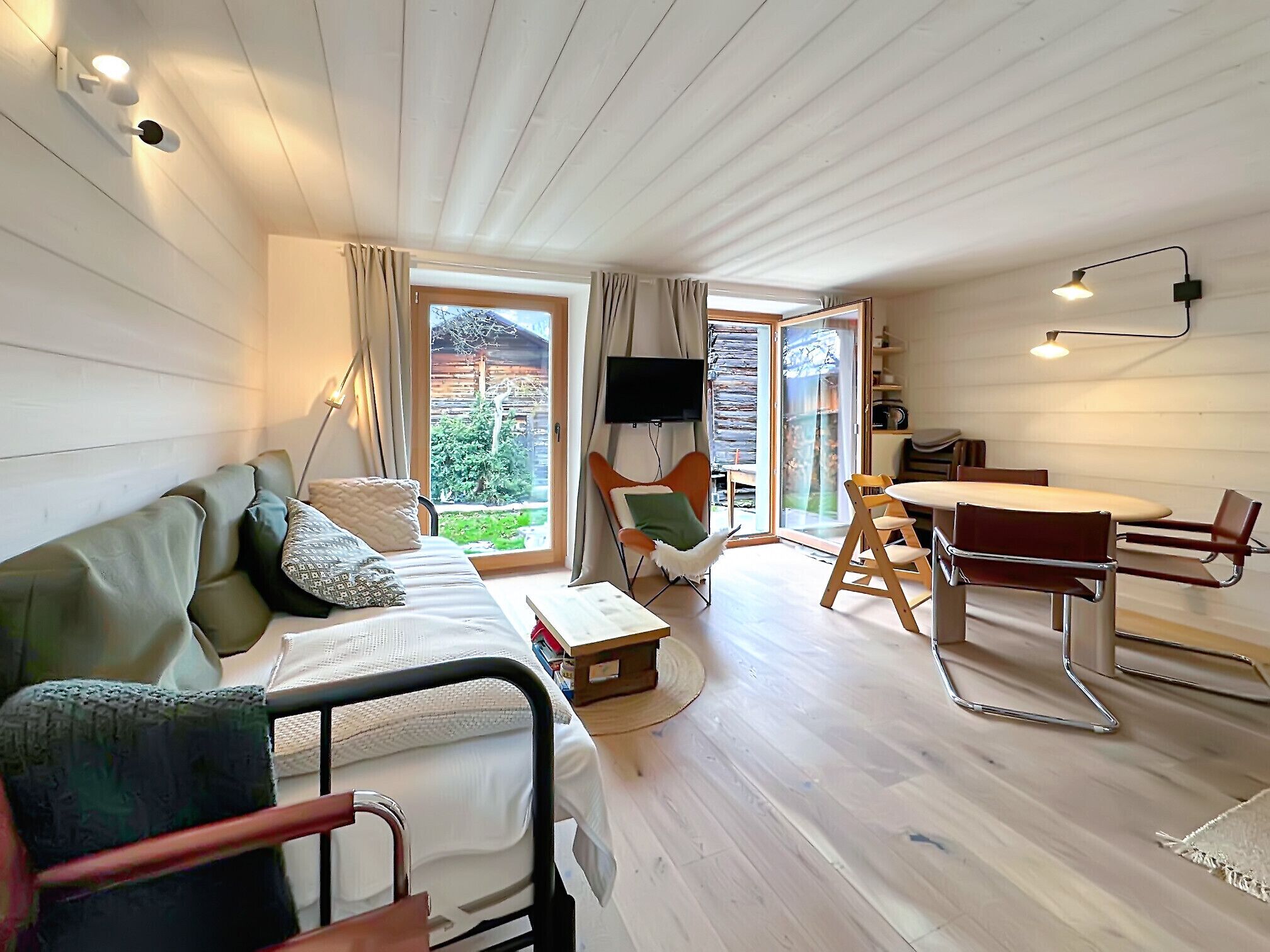 A modern room with a bed, a dining table, and a TV.