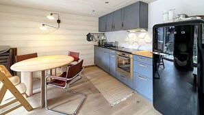 A modern kitchen with a wooden table, a chair, and a built-in oven. - Perfect Lodge 10 mns from Verbier - 4 Valleys . Sw (Sarreyer)