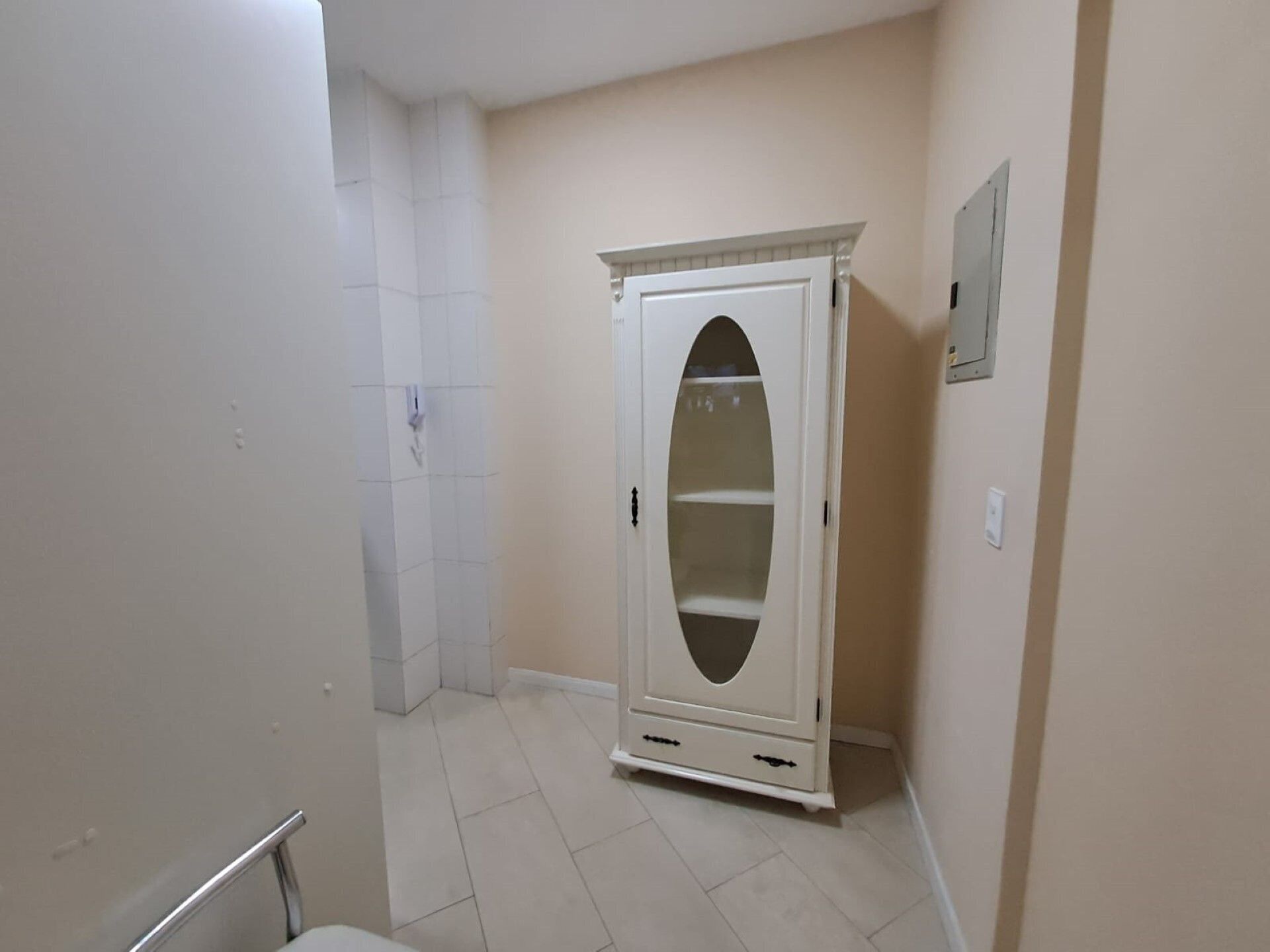 Ein Eckzimmer mit einem weißen Kleiderschrank, einer weißen Tür und einem weißen Fliesenboden.