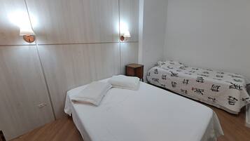 A room with a bed, a bedside table, and a wall-mounted lamp.