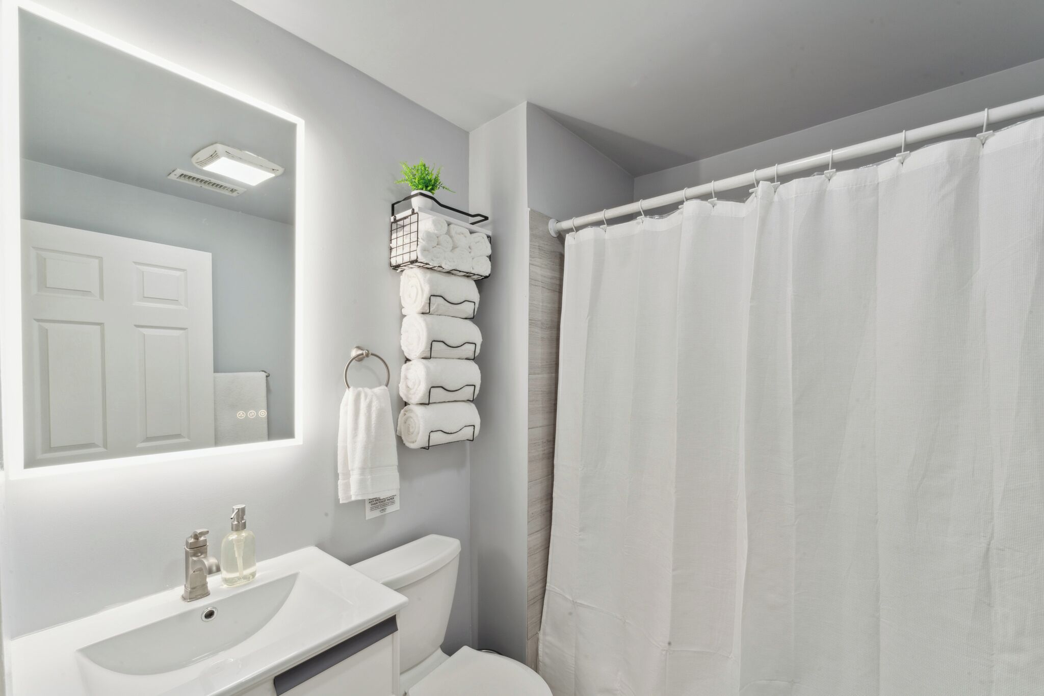 A bathroom with a white sink, toilet, and shower curtain.