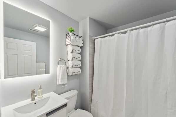 Un baño con lavamanos, inodoro y cortina de ducha blancos.