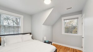 Un dormitorio con una cama, una mesita de noche, una ventana y una puerta.