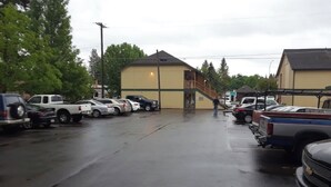 A parking lot with several cars and a building with a ramp leading to a porch. - Coeur D'Alene Budget Saver (Coeur d'Alene)