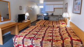A hotel room with a large bed, a desk, a television, a small kitchenette, and a mirror. - Coeur D'Alene Budget Saver (Coeur d'Alene)