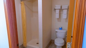 A small bathroom with a shower, toilet, and a towel rack. - Coeur D'Alene Budget Saver (Coeur d'Alene)
