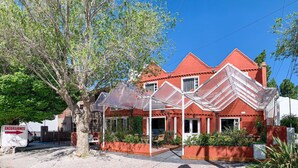 Une maison en briques rouges dotée d’un patio couvert et d’une enseigne indiquant « Excursions ».