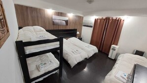 Une chambre d’hôtel avec des lits superposés, un téléviseur à écran plat, un radiateur et une fenêtre avec des rideaux.