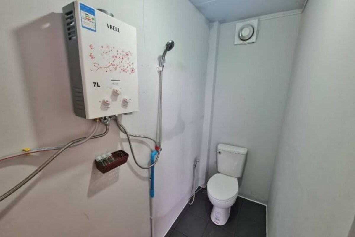 A bathroom with a toilet, a shower, and a water heater mounted on the wall.