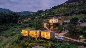 A hillside village with wooden structures and a dirt road. - Mankhao Homestay (Mae Rim)