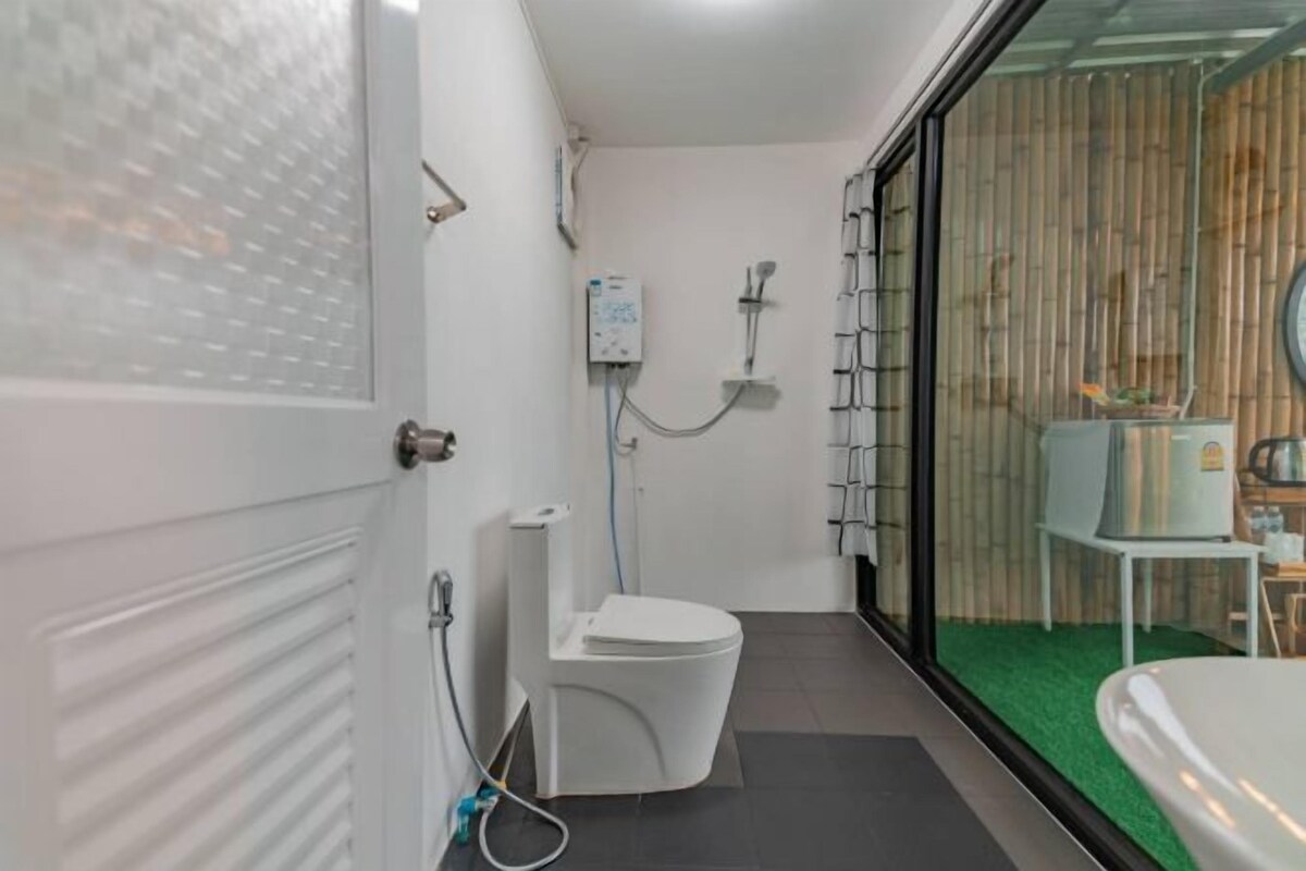 A compact bathroom with a toilet, shower, and a small table with a water heater.